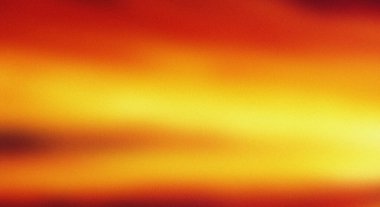 Koyu kırmızıdan parlak sarı ve turuncu renklere geçiş yapan, ılık renklerin değişimine sahip, taneli dokulu soyut bir arka plan..