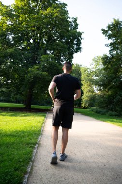 Gri spor ayakkabılı adam dışarıda yürüyor.