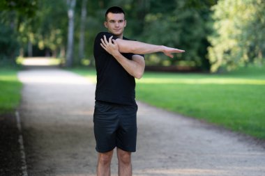 Parkta kolunu uzatan adam.