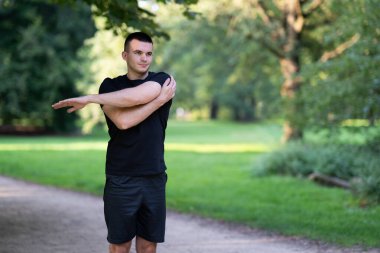 Parkta kolunu uzatan adam.