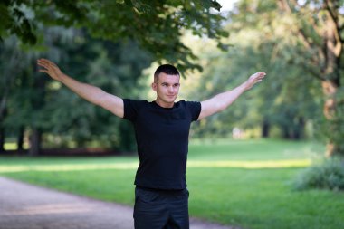 Parkta kollarını açan bir adam