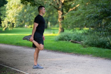 Adam parkta bacağını esnetiyor.