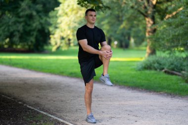 Adam parkta bacağını esnetiyor.