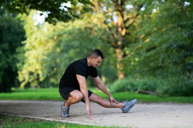 Adam parkta bacağını esnetiyor.