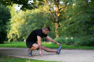 Adam parkta bacağını esnetiyor.