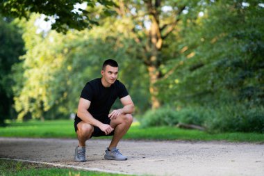 Park yolunda çömelmiş bir adam