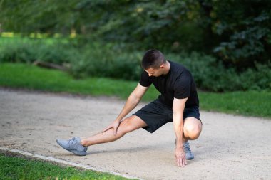 Adam parkta bacağını esnetiyor.