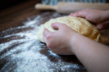 Mutfak masasında çiğ hamur tutan eller. Ev yapımı pişirme hazırlama süreci.