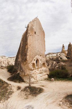 Dağların vadisindeki kapadokya manzarası ve kayadan oyulmuş antik bina.