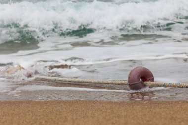 Denizde deniz dalgası, sahilde bir kablo şamandırasının yakınında.
