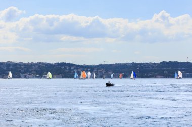 Boğazda hızla ilerleyen özel bir tekne ve Boğaz Kupası için yarışan yelkenliler.