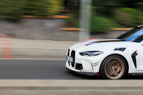 Yoldaki beyaz spor bir arabanın pan fotoğrafı, çevirme tekniği.