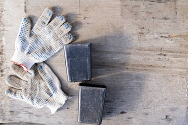 Bahçe aletleri, eldivenler ve güzel çiçekler, çimento arka planda yapraklar ve bitkiler. Bahçe ve peyzaj konsepti