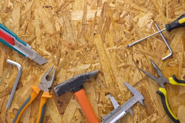 A variety of used tools on an OSB plywood background