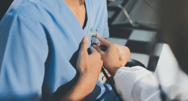 Bir doktor klinik randevusu sırasında hastanın kalbini incelemek için steteskop kullanır..