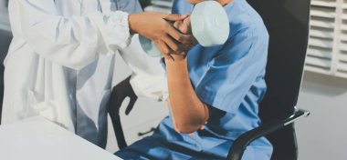 Hemşirenin desteğiyle el ağırlığı kullanan kişi