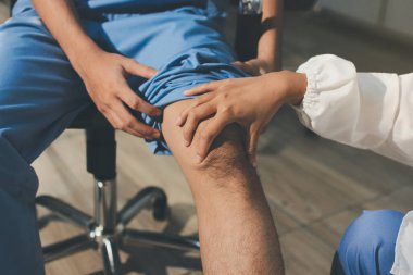 Fizyoterapist hastaya diz ağrısı için egzersiz yapmayı öğretiyor.