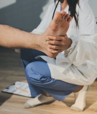 Fizyoterapist hastaya diz ağrısı için egzersiz yapmayı öğretiyor.