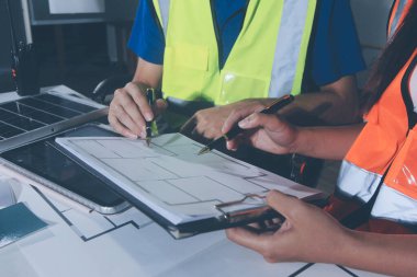 Endüstriyel mühendislerden oluşan bir ekip, fabrikadaki masada bulunan makine planlarını analiz ediyor. Fabrikada ya da üretim tesisinde çalışıyorum..