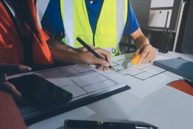 Endüstriyel mühendislerden oluşan bir ekip, fabrikadaki masada bulunan makine planlarını analiz ediyor. Fabrikada ya da üretim tesisinde çalışıyorum..