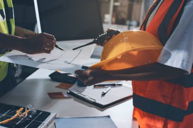 Endüstriyel mühendislerden oluşan bir ekip, fabrikadaki masada bulunan makine planlarını analiz ediyor. Fabrikada ya da üretim tesisinde çalışıyorum..