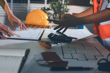 Endüstriyel mühendislerden oluşan bir ekip, fabrikadaki masada bulunan makine planlarını analiz ediyor. Fabrikada ya da üretim tesisinde çalışıyorum..