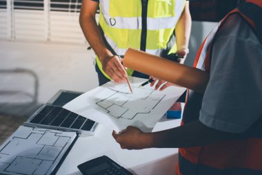Endüstriyel mühendislerden oluşan bir ekip, fabrikadaki masada bulunan makine planlarını analiz ediyor. Fabrikada ya da üretim tesisinde çalışıyorum..