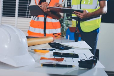 Endüstriyel mühendislerden oluşan bir ekip, fabrikadaki masada bulunan makine planlarını analiz ediyor. Fabrikada ya da üretim tesisinde çalışıyorum..