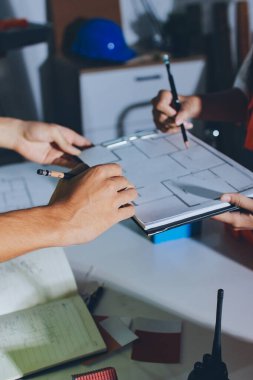 Endüstriyel mühendislerden oluşan bir ekip, fabrikadaki masada bulunan makine planlarını analiz ediyor. Fabrikada ya da üretim tesisinde çalışıyorum..