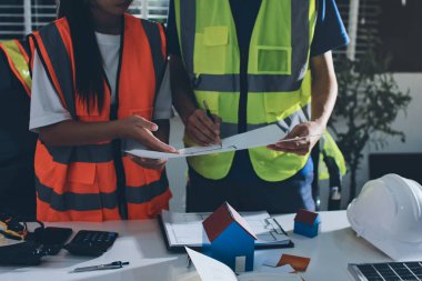 Endüstriyel mühendislerden oluşan bir ekip, fabrikadaki masada bulunan makine planlarını analiz ediyor. Fabrikada ya da üretim tesisinde çalışıyorum..