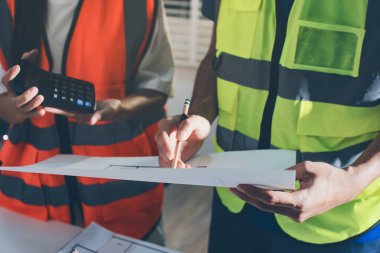 Endüstriyel mühendislerden oluşan bir ekip, fabrikadaki masada bulunan makine planlarını analiz ediyor. Fabrikada ya da üretim tesisinde çalışıyorum..