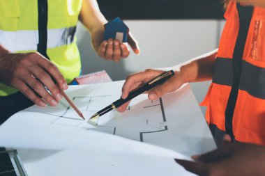 Endüstriyel mühendislerden oluşan bir ekip, fabrikadaki masada bulunan makine planlarını analiz ediyor. Fabrikada ya da üretim tesisinde çalışıyorum..