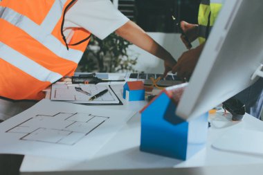 Endüstriyel mühendislerden oluşan bir ekip, fabrikadaki masada bulunan makine planlarını analiz ediyor. Fabrikada ya da üretim tesisinde çalışıyorum..