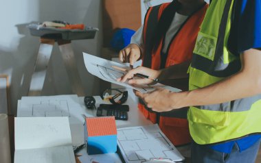 Endüstriyel mühendislerden oluşan bir ekip, fabrikadaki masada bulunan makine planlarını analiz ediyor. Fabrikada ya da üretim tesisinde çalışıyorum..