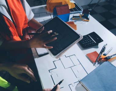 Endüstriyel mühendislerden oluşan bir ekip, fabrikadaki masada bulunan makine planlarını analiz ediyor. Fabrikada ya da üretim tesisinde çalışıyorum..