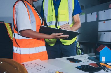 Endüstriyel mühendislerden oluşan bir ekip, fabrikadaki masada bulunan makine planlarını analiz ediyor. Fabrikada ya da üretim tesisinde çalışıyorum..