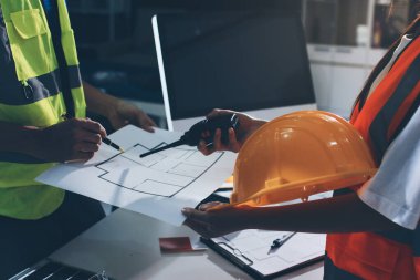 Endüstriyel mühendislerden oluşan bir ekip, fabrikadaki masada bulunan makine planlarını analiz ediyor. Fabrikada ya da üretim tesisinde çalışıyorum..