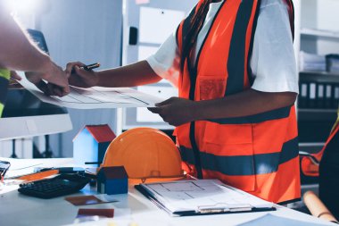 Endüstriyel mühendislerden oluşan bir ekip, fabrikadaki masada bulunan makine planlarını analiz ediyor. Fabrikada ya da üretim tesisinde çalışıyorum..