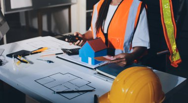 Endüstriyel mühendislerden oluşan bir ekip, fabrikadaki masada bulunan makine planlarını analiz ediyor. Fabrikada ya da üretim tesisinde çalışıyorum..