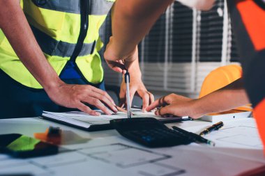 Endüstriyel mühendislerden oluşan bir ekip, fabrikadaki masada bulunan makine planlarını analiz ediyor. Fabrikada ya da üretim tesisinde çalışıyorum..