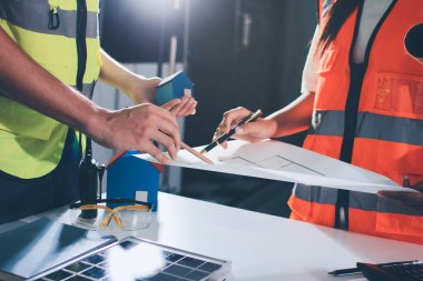 Endüstriyel mühendislerden oluşan bir ekip, fabrikadaki masada bulunan makine planlarını analiz ediyor. Fabrikada ya da üretim tesisinde çalışıyorum..