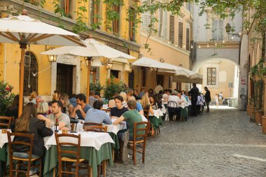 Roma, İtalya - 18 Nisan 2017: İnsanlar Roma 'nın tarihi bölgesi Trastevere' de tipik bir açık hava lokantasında yemek yiyorlar.