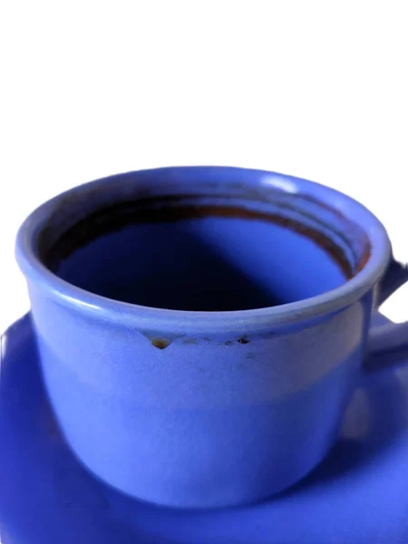 Mavi seramik çay fincanının yakın çekimi, koyu sıvıya ve desenli kenarına odaklanıyor..