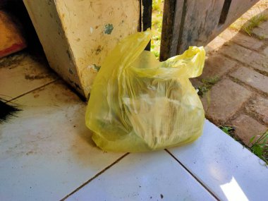 Plastik çöp torbası, güneş ışığının filtrelediği fayanslı bir yüzeye atılmış.