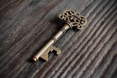 Ahşap yüzeyde duran karmaşık tasarımları olan antik anahtar.