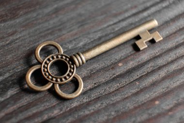 Ahşap yüzeyde duran karmaşık tasarımları olan antik anahtar.