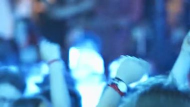 İnsanlar konserde, eller havaya, ritimle dans ediyorlar.