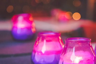 Hygge kavramı. Parlak koyu masanın üstüne mor ve pembe mum yakma