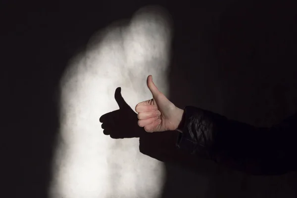 Woman hand thump up sign and shadow on a wall