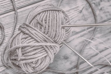 Gri iplik ve örme iğneler gri ahşap arka plan üzerinde topu